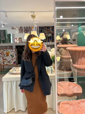 Ribbad brun långklänning Adoore - Säljer en ribbad brun långklänning med ärmlös design och rund halsringning. Klänningen har en kroppsnära passform och är tillverkad i ett stretchigt material som ger en snygg siluett. Perfekt för dig som gillar stilrena och trendiga plagg. Är från Adoore