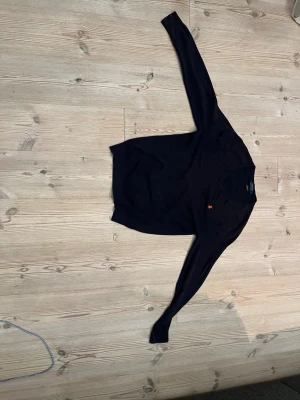 Mörkblå tröja med orange logga - Mörkblå långärmad tröja med rund hals och en liten orange Ralph lauren logga broderad på bröstet. Har knappts användts.