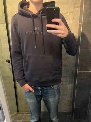 Svart hoodie från J.Lindeberg - Mörkblå hoodie från J.Lindeberg. Använts en del men fortfarande i bra skick.