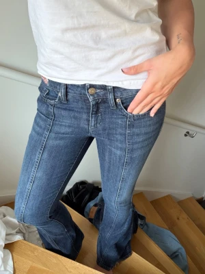 Blå bootcut jeans med markerad söm - Säljer ett par blå bootcut jeans med markerad söm framtill. Jeansen har klassisk femficksmodell, normalhög midja och lätt utsvängda ben. Materialet är denim i bomull med lite stretch för skön passform. Perfekta till sneakers eller boots!