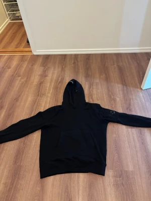 Svart hoodie från C.P. Company - Snygg svart hoodie från C.P. Company med klassisk känguruficka framtill och huva med dragsko. Perfekt för dig som gillar streetwear och vill ha en stilren look. Tillverkad i mjukt material som känns skönt mot huden. Den är Storlek XL men sitter som M. Pris kan diskuteras vid snabb försäljning