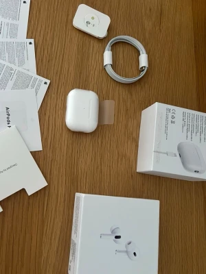 Apple AirPods Pro 2 - Säljer ett par vita Apple AirPods Pro med laddningsetui och tillbehör. Hörlurarna är in-ear och levereras med originalförpackning, laddkabel och manualer. Perfekt för dig som vill ha grymt ljud, aktiv brusreducering och smidig anslutning.