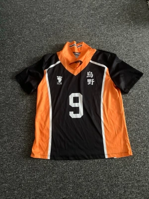 Haikyuu Karasuno volleybolltröja cosplay - Säljer en svart och orange volleybolltröja från anime-serien Haikyuu, Karasuno lagets nummer 9. Tröjan har vita detaljer, korta ärmar och tryckta japanska tecken samt siffran 9 fram och bak. Perfekt för cosplay eller maskerad.