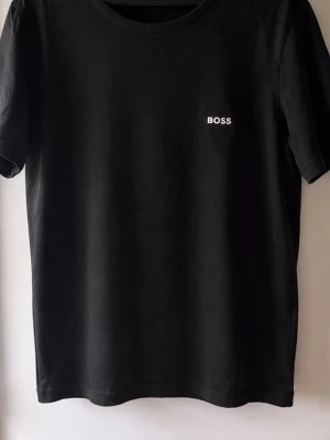 Svart t-shirt från BOSS - Klassisk svart t-shirt från BOSS med enkel vit logga på bröstet lätt att matcha med allt. Strl XL men passar L bättre