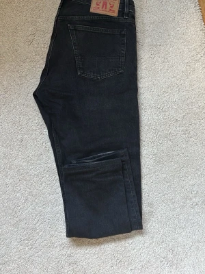 Svarta jeans från Kings Of Indigo - Snygga svarta jeans från Kings Of Indigo med klassisk femficksmodell och raka ben. Jeansen har en mörk tvätt och är tillverkade i slitstarkt denimtyg. Perfekta för en avslappnad och trendig stil. Storlek 31W och 30L