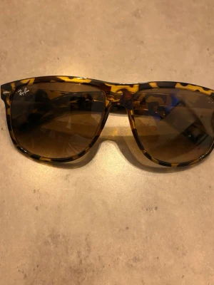 Ray-Ban solglasögon leopardmönster - Snygga Ray-Ban solglasögon med klassisk wayfarer-form och leopardmönstrad båge i bruna och gula toner. Glasen är mörka och ger en cool vibe till din look. Perfekta för soliga dagar och för dig som vill sticka ut lite extra. Jätte snygga. Mycket bra skick. Mitt pris 429 pris kan diskuteras vid snabb affär.