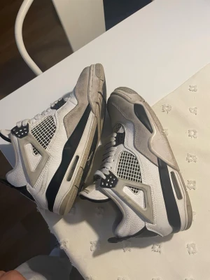 Vita och grå sneakers med meshdetaljer - Snygga sneakers i vitt och grått med svarta detaljer och meshpaneler på sidorna. Skorna har en chunky sula och coola plastdetaljer vid snörningen. Perfekta för dig som gillar streetwear och vill ha en stilren men ändå sportig look.