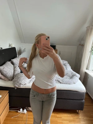 Vit croppad t-shirt - Säljer en enkel och stilren vit croppad t-shirt med korta ärmar och rund hals. Perfekt till jeans eller kjol för en avslappnad look. Materialet känns mjukt och lätt, troligen bomull eller en bomullsblandning.