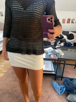Svart virkad stickad tröja - Snygg svart stickad tröja med virkat hålmönster och trekvartsärmar. Tröjan har rund halsringning och är lätt transparent, perfekt att styla över ett linne eller topp. Materialet känns lite ”plastigt” men den är inte obekväm. 