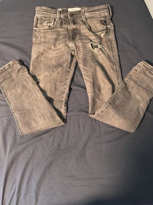 Replay grå ripped jeans - Säljer nu dessa grå replay ripped i storlek 28/30 dom har ett litet hål strax under dragkedjan som visas på bild men inte några andra icke-kosmetiska hål så mycket jag vet🙌🤩🍾