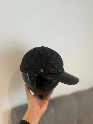 Gg keps  - Gg keps svart med en silver symbol som står gg och gg mönster som är också lite gråa