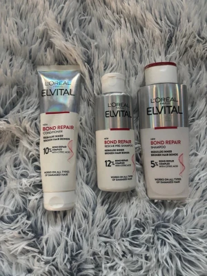 L'Oréal Elvital Bond Repair set - Säljer ett set med L'Oréal Elvital Bond Repair produkter: balsam, rescue pre-shampoo och schampo. Förpackningarna är vita och silverfärgade med röda detaljer. Produkterna innehåller citronsyra och är anpassade för skadat hår. Använd 2 gånger