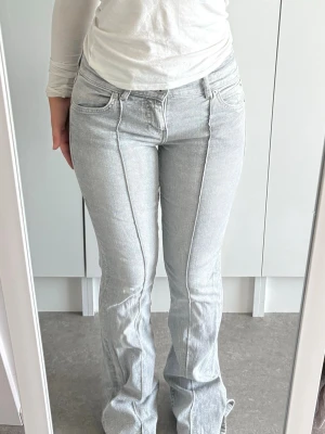 Ljusgrå bootcut jeans med pressveck - Säljer ett par ljusgrå jeans med bootcut-modell och markerade pressveck framtill. Jeansen har klassisk femficksdesign, normal midja och stängs med dragkedja och knapp. Materialet är stretchigt denim som sitter snyggt och bekvämt.