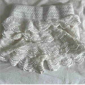 virkade shorts med volanger - Supersöta shorts med virkade detaljer och flera lager volanger. De har hög midja och ett elastiskt midjeband för skön passform. Perfekta för varma dagar och ger en romantisk och bohemisk vibe.