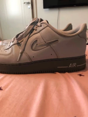Nike Air Force 1 grå sneakers - Säljer ett par klassiska Nike Air Force 1 sneakers i ljusgrått med mörkgrå sula och silverfärgad swoosh. Skorna har lågt skaft, snörning och är tillverkade i läder. Perfekta för dig som vill ha en clean och stilren look.