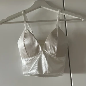 Topp - Säljer en oanvänd vit topp i glansigt tyg. Supersöt! 