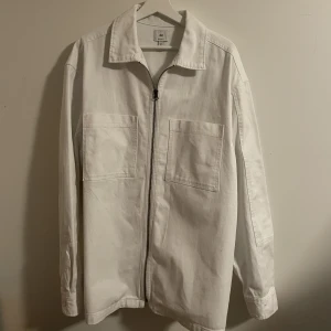 HM Overshirt - Snygg vit overshirt från HM i storlek L. Den är i toppskick och knappt använd. Finns inga tecken på användning. Tunt och skönt material, relaxed fit. Fler bilder kan fixas vid intresse.