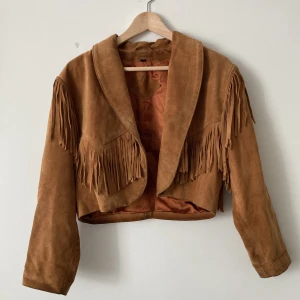 Vintage Mockajacka med fransar - Suuuuperskön och mjuk. Croppad. Innertyget är i satin och utsidan äkta läder. Tecken på användning men inget som utmärker sig, fortf mkt fin! Passar   XS-S.