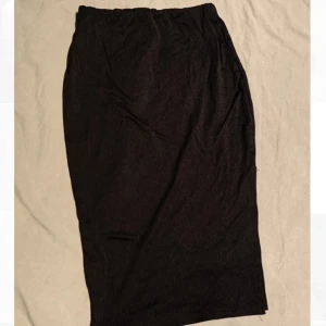 Svart kjol - En svart ribbad medelång kjol, med ett slit på sidan.