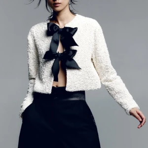 Paljettklädd topp med rosetter - Jättefin topp från H&M i vitt med svarta rosetter. Glittrar jättefin i verkligheten. Storlek S, slutsåld på hemsidan. Perfekt till nyår. Kan även användas bak och fram med rosetterna på ryggen!