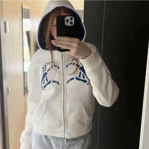 Ziphoodie  - Vit zipup hoodie med blått tryck i fint skick! En favorit tröja men säljer då jag inte fått användning för den på länge