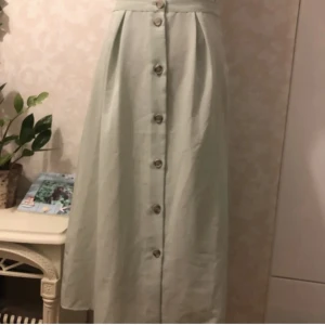 Lång kjol - En högmidjad, lång kjol med knappar. Midjan är stretchig på baksidan och kjolen sitter jättefint. Jag är 175 cm som referens för längden. 