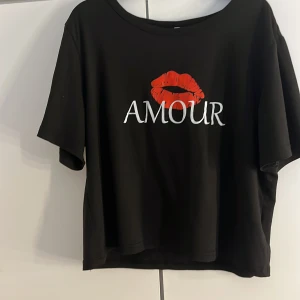 Svart T-shirt med byxor till - En svart T-shirt mer tryck. Den är väl använd men har inga defekter och är i ett väldigt bra skick. Även byxor får man med som ett sätt