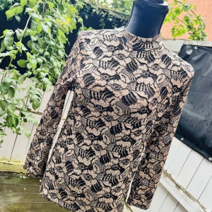 Tjusig fest polotopp  - Tjusig fest polotopp med blomtryck Färg :guld/beige