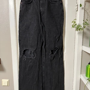Långa vida jeans  - Svarta jeans med vida ben, har hål på knäna. Stl. 30/38  Jag är 190 och benen nuddar vid skorna.