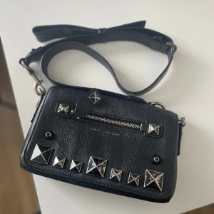 Marc Jacobs väska - Marc Jacobs väska som är köpt på plick för ca 900kr. Väskan är i ett använt men fint skick, bandet går att justera och den sitter väldigt fint på när man bär den. Rymmer allt man behöver under dagen och är supersnygg. Säljer då jag inte använder den!