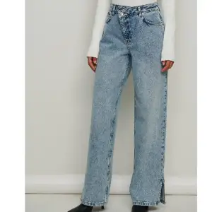 Syratvättade jeans med asymmetrisk midja från NA-KD💗Väldigt coola jeans som har en klassisk ljusblå färg, asymmetrisk midja och slits! De är använda en gång och är i utmärkt skick. 