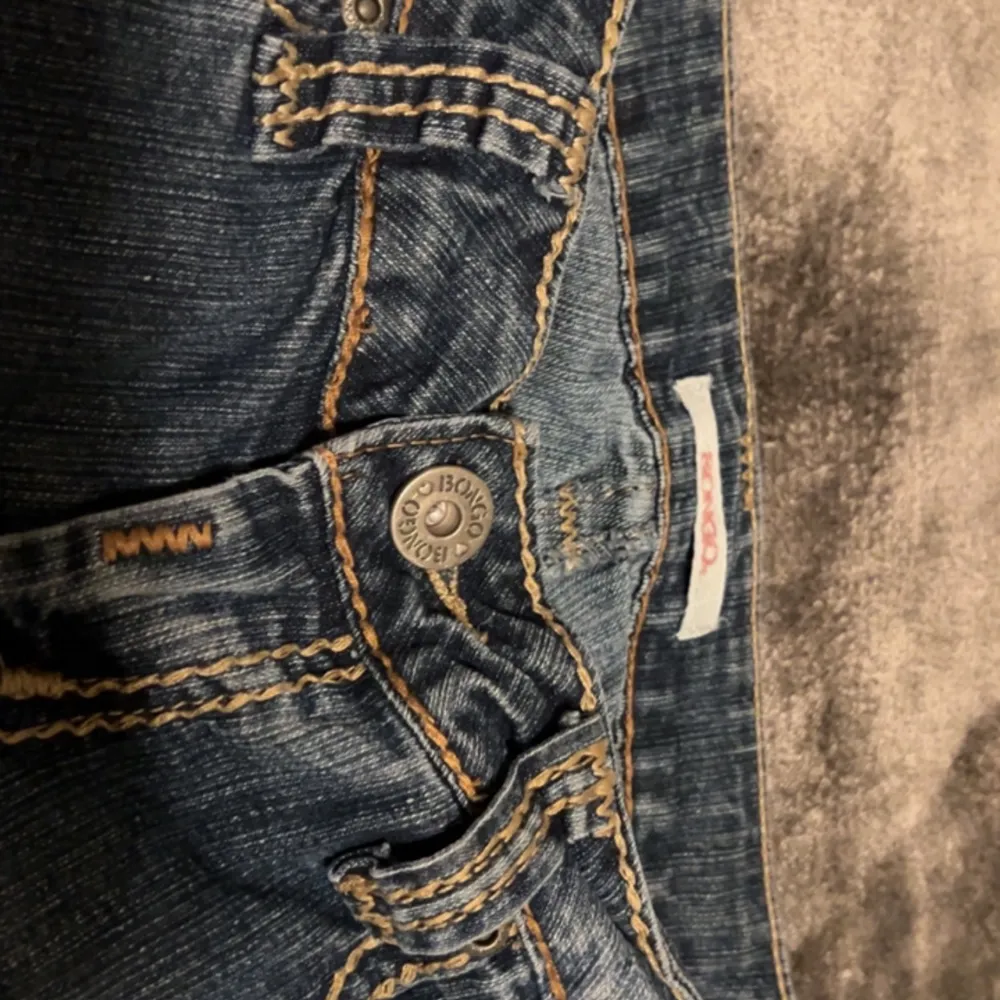 Snygga lågmidjade jeans i bootcut/flare modell med fina beiga detaljer!! Kan absolut skicka fler bilder om behövs!🫶 Innberbenslängden: 80 cm Midjemåttet: 38 cm (tvärsöver). Jeans & Byxor.