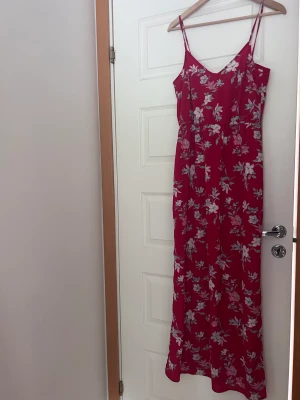 Röd långklänning  - En röd långklänning med Blom detaljer. Köpt på hm. Använt en gång! Passar så bra till dop/ bröllop men även middag eller liknande. Har resor under bysten. Så så så fin! 