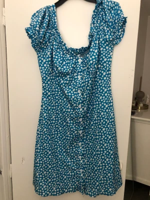 Blå blommig klänning  - Korsettliknande klänning som är figursydd vid bysten. Använd 1 gång så som ny. Köpt från märket: Not your honey. 