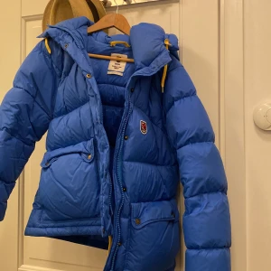 Fjällräven jacka  - Jag säljer min jacka då den inte kommer till användning. Jackan ser skrynklig ut då den varit inne i garderoben hela sommaren men det försvinner om man hänger upp den eller lämnar in på kemtvätt. Jackan är i superbra skick och användes i vintras