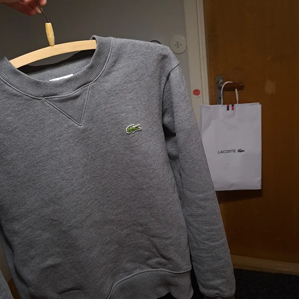 Grå Lacoste sweatshirt som var köpt i stockholm. (Nypris 1,200kr) Tröjan är i XS men passar även S. Väldigt lite använd och kommer i en lacoste bag. Skriv för bilder och frågor!. Hoodies.