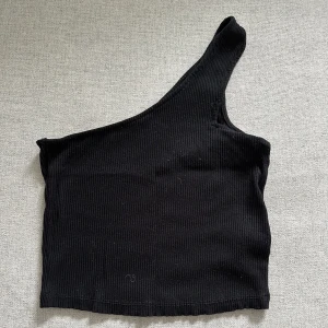 Svart one shoulder topp - Topp från naked, one shoulder. Den är croppad. 