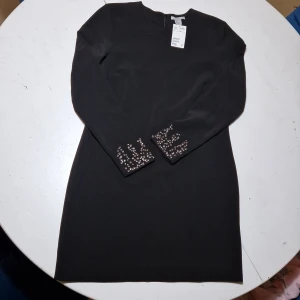 Oanvänd klänning  - Stilren klänning som är helt oanvänd. Fina detaljer vid ärmslutet. 