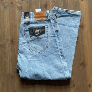 Helt nya Levis 501 93’, storlek W38 - Säljer två par jeans, denna annons är för ett par blå Levi’s 501 93’s. Båda jeans har sina tags kvar och är oanvända.  De blå jeans har hål och markeringar kring hål som är är gjorda av tillverkarna. Pris på Levis Store just nu: 1019kr