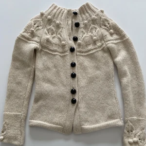 Stickat kofta från By Malene Birger, stl M - Härlig stickat kofta i ull från By Malene Birger. 80% ull och 30% alpacka. Färg offwhite. Mörk bruna rundade knappar. Lätt insvängt modell. 