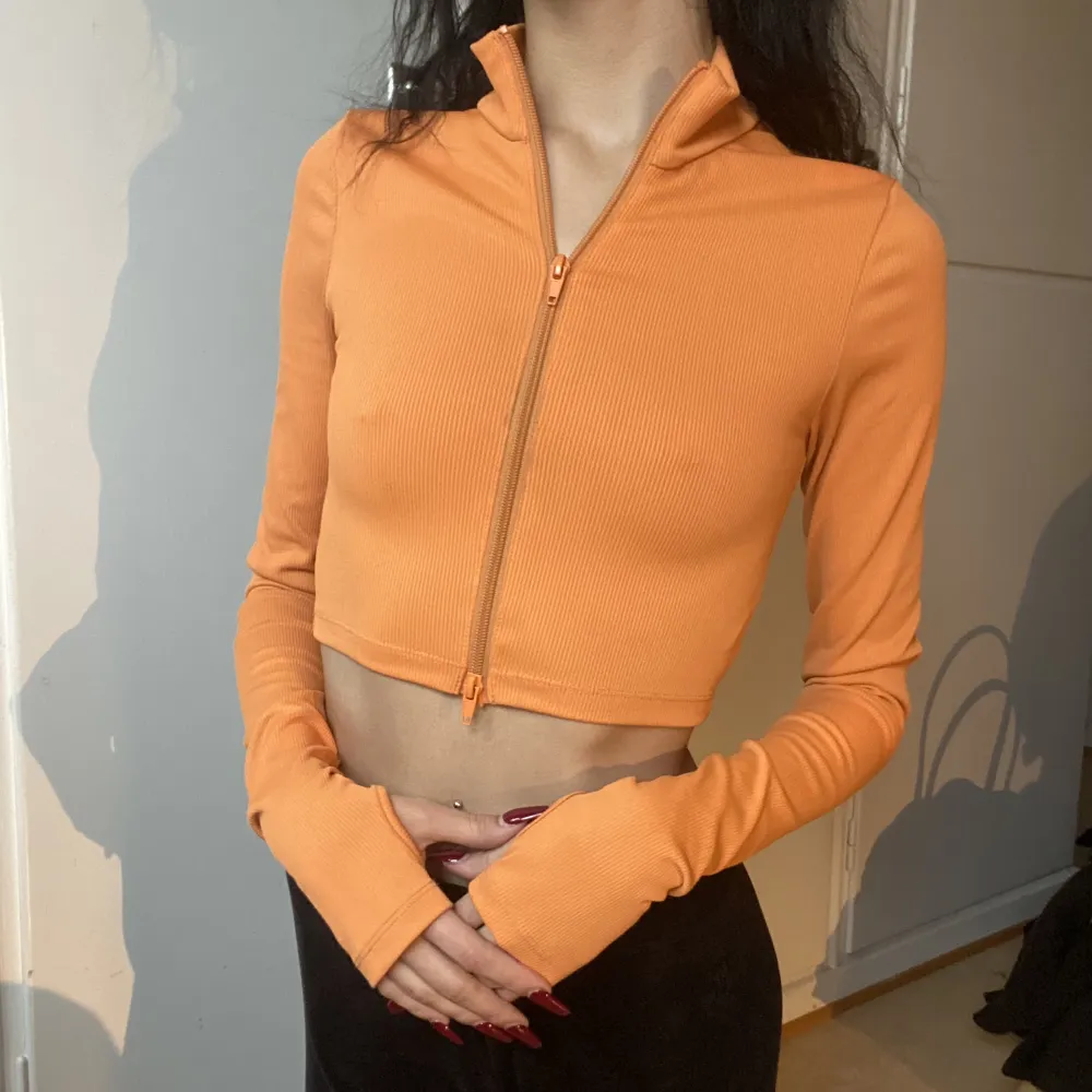 Skitsnygg ribbad orange långärmad tröja med tumhål samt dragkjedja man kan öppna från båda hållen, vilket gör att man kan bära denna tröjan på olika sätt🤩  . Toppar.