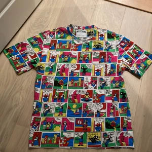 Moschino T-Shirt Serietidning design - Säljer den då den aldrig används. Använd 1 gång och är i perfekt och rent skick. Nypris 2300kr+