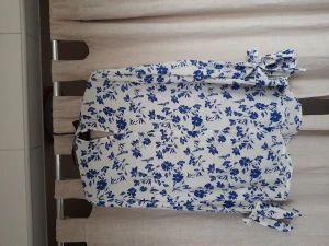 Blommig blus - Fin blommig och luftig blus från stockh lm i storlek 36. Blusen har fina detaljer nere på ärmarna med små knappar och även band att knyta en rosett med.  Uptäckte tyvörr att busen har gulnat lite vid armhålorna, synns bara på nära håll.