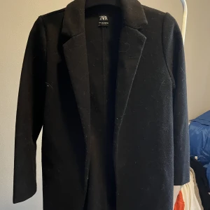 Kappa - Svart kappa som inte har några knappar 