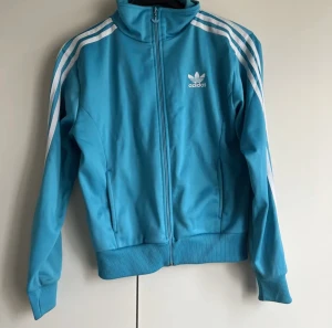 Adidas tröja - Säljer den här fina adidas zip up, några små fläckar kan förekomma💕 vet inte om det går bort i tvätten men det borde(lånade bilder från förra ägaren)