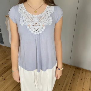 Ljusblå topp - Säljer en superfin ljusblå topp med virkade detaljer, den är i bra skick men har ett pyttelitet knappt synligt hål där fram som enkelt går att sy igen om man tycker att det behövs.