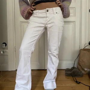 Lågmidjade bootcutjeans  - Vita lågmidjade bootcutjeans med detaljer på fickorna. Det står storlek 30 i byxan men antar att det är ungefär s/m😊