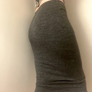 Basic mörkgrå långkjol - Tight mörkgrå kjol som slutar nedanför knäna på mig som är 165 cm. Ganska stretchigt material. Funkar nog även att ha som klänning. Kan mötas upp nära Mariatorget eller posta. 