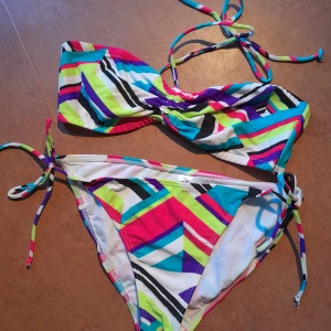 Färgglad bikini 👙 - En bikini i knyt-modell, mönstrad i starka fina färger. Den är från Stadium, storlek 40 men inte jättestor. Det finns en mycket liten defekt, se sista bilden. 