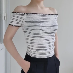Off shoulder topp  - Vit- och svartrandig, ribbad off shoulder topp med krusade kanter. Mycket stretchig i mjukt tyg, i bra skick. 